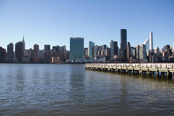 Edifícios em Manhattan e East River de Gantry Plaza State Park vista
 - Foto, Imagem