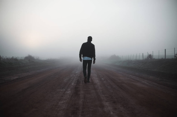 Άνδρα με τα πόδια μακριά στον ομιχλώδη δρόμο - Φωτογραφία, εικόνα