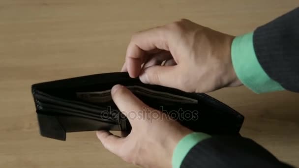 Ένας άνθρωπος που παίρνει έξω τραπεζογραμματίων από ένα δερμάτινο τσαντάκι - Πλάνα, βίντεο