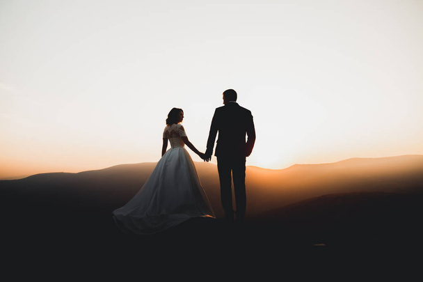Happy beautiful wedding couple bride and groom at wedding day outdoors on the mountains rock. Happy marriage couple outdoors on nature, soft sunny lights - Foto, Bild