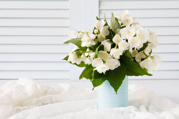 Fresh jasmine flowers in a vase on wooden background - Photo, Image