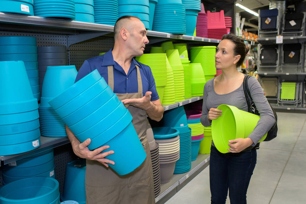 sales assistant helping female buying pots in store - Photo, Image
