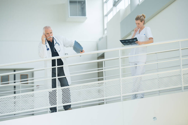 doctor nd nurse in hospital corridor resting against balcony - Zdjęcie, obraz