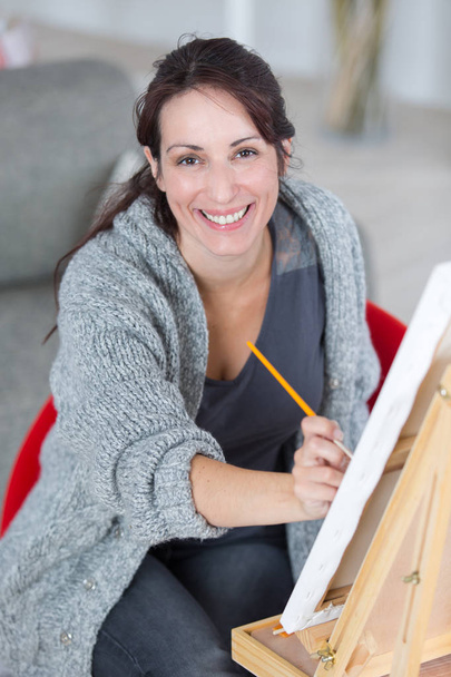 female artist working on painting in bright daylight studio - Fotografie, Obrázek