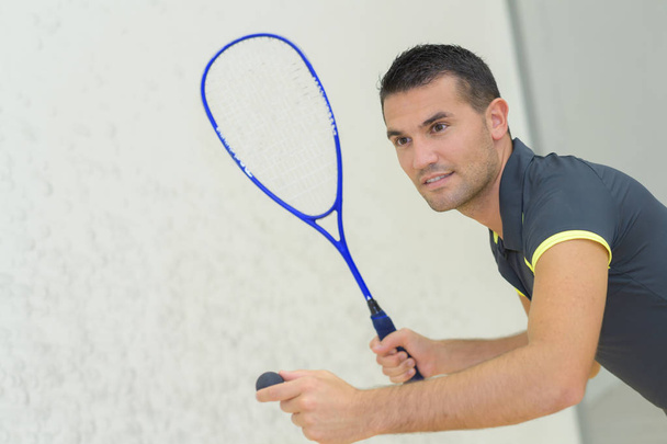 low angle view of determined young man playing tennis indoor - Фото, изображение