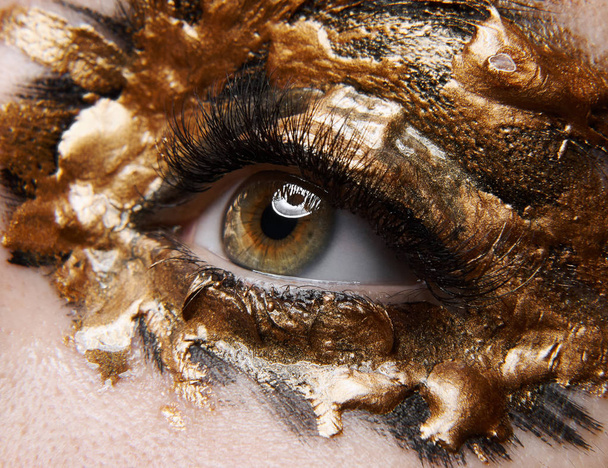 Macro and close-up creative make-up theme: beautiful female eye with golden black paint, retouched photo - Fotó, kép