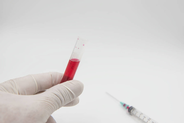sample blood tube in hand and syringe on a white background.  - Photo, Image