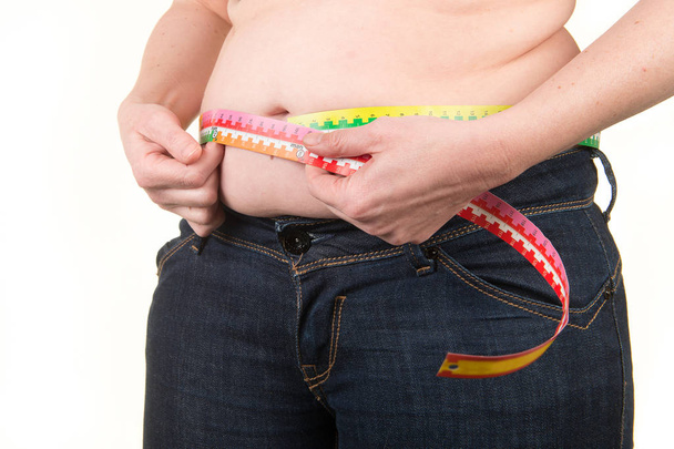 Overweight Woman measuring belly fat with measure tape on a white background - Photo, Image