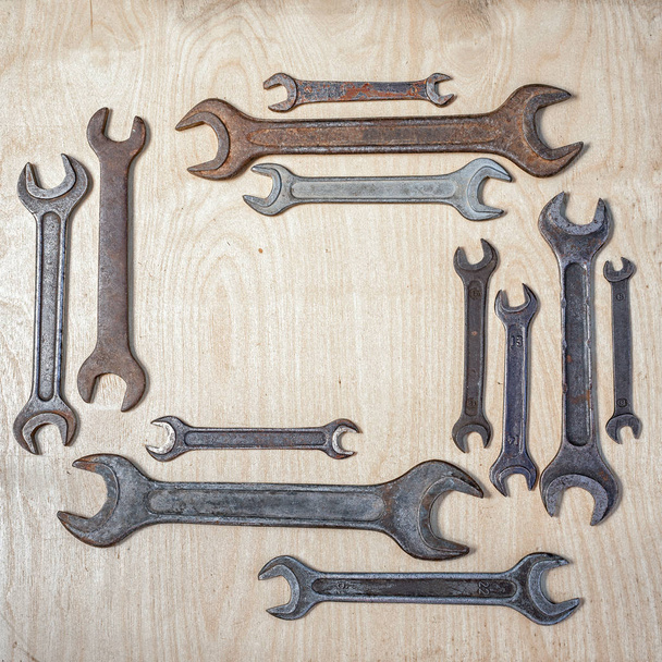 прямокутна рамка старих іржавих гайкових ключів на дерев'яному фоні, з копіювальним простором всередині
 - Фото, зображення