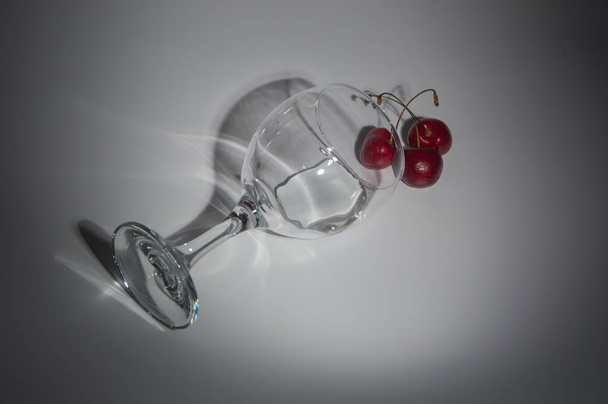 a glass of water and cherries on a white background. - Zdjęcie, obraz