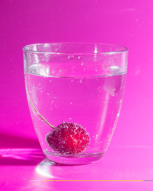 on the pink background of the cherry in the glass with bubbles. - Fotografie, Obrázek