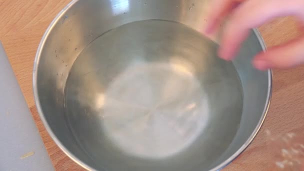 Uma mulher coloca lençóis de gelatina em uma tigela com água
 - Filmagem, Vídeo