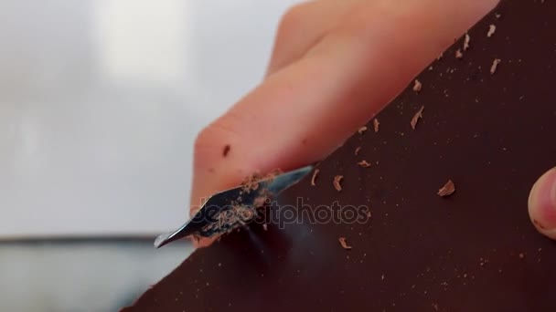 Una donna grattugia una tavoletta di cioccolato con un pelapatate
  - Filmati, video