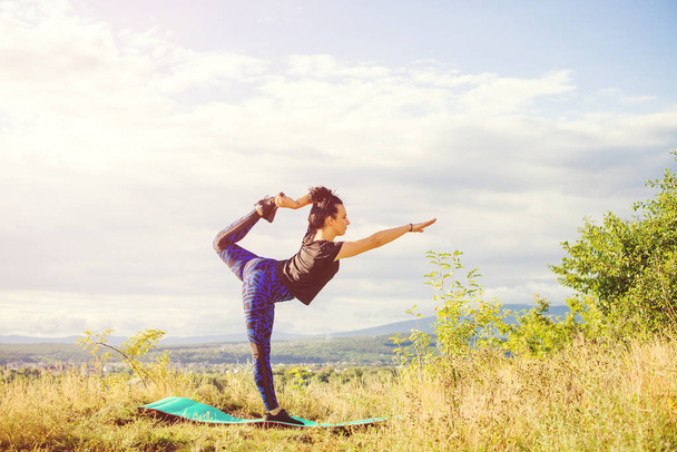 Jovem fazendo ioga ou exercício de fitness ao ar livre, paisagem da natureza ao pôr do sol
. - Foto, Imagem