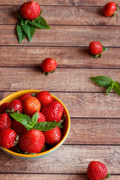 Juicy fresh strawberries in a bowl on wooden background, selective focus - Foto, Imagem