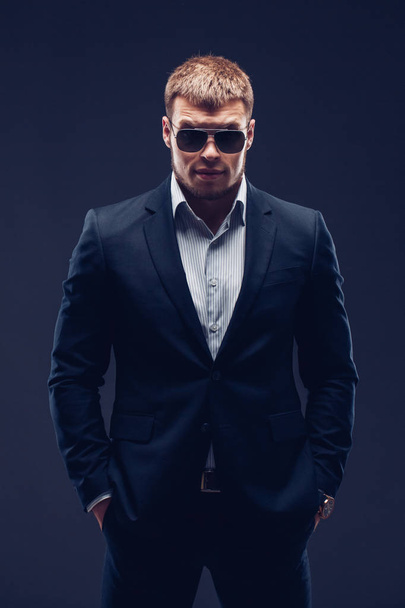 Fashion young businessman black suit on dark background - Fotó, kép