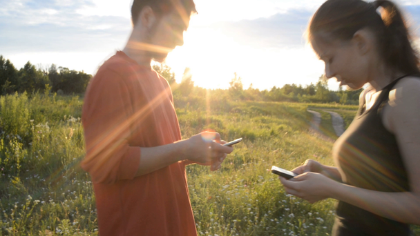 Girl and guy in the nature looking in a mobile phone - Footage, Video