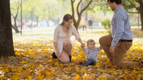 Images au ralenti d'une jeune mère et d'un jeune père tenant leur fils par les mains et marchant au parc d'automne
 - Séquence, vidéo