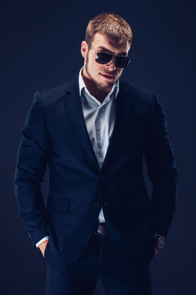 Fashion young businessman black suit on dark background - 写真・画像