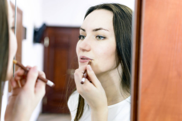 beautiful girl paints lips in the office - Fotó, kép