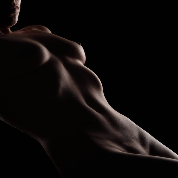 Sexy nude woman body lying over black studio background - 写真・画像
