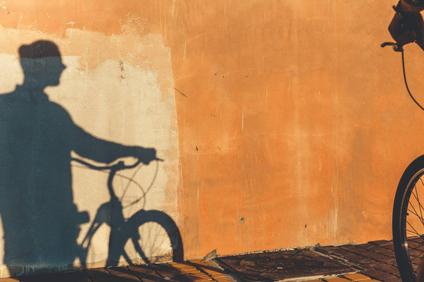 Shadow Of Unrecognizable Male Cyclist On A Colorful Wall Daily Routine Lifestyle - Foto, imagen