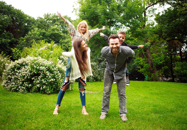 Happy joyful family in park fun playing imitation flight - Zdjęcie, obraz