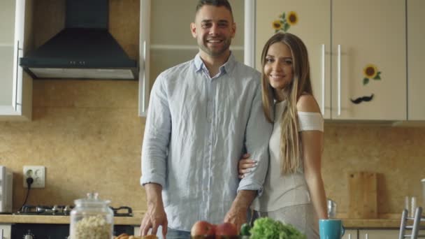 Portré szerető pár mosolygó ang vizsgálja a fényképezőgép otthon a konyhában - Felvétel, videó