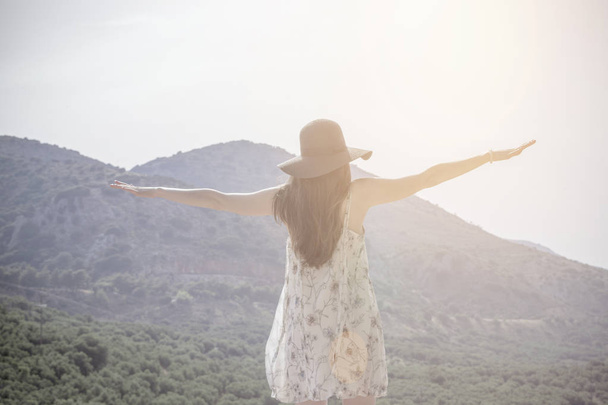 Beautiful woman standing on top of mountain and stretching out hands. Concept - freedom, to go abroad, travel, happiness, stereotypes, to break the frame - Foto, Bild