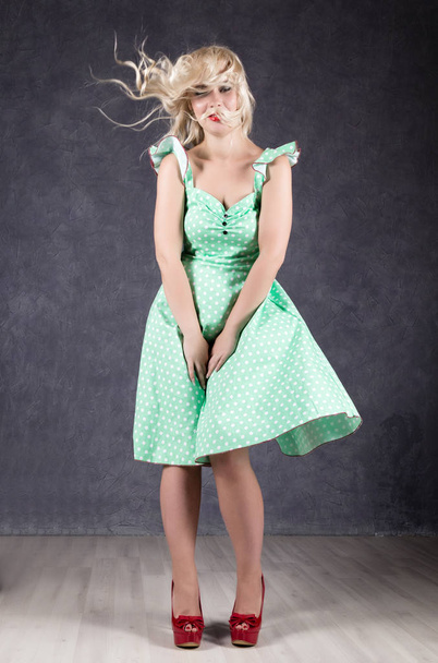 blonde woman with hair in the wind. sexy girl with flying hair posing in green dress and red shoes - 写真・画像