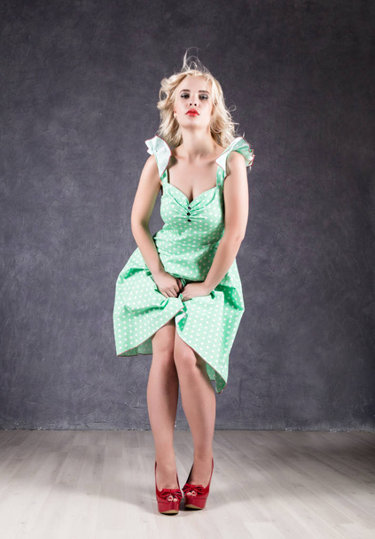 blonde woman with hair in the wind. sexy girl with flying hair posing in green dress and red shoes - Foto, immagini