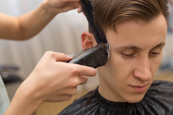 Master leikkaa miesten hiuksia parturissa, kampaaja tekee kampauksen nuorelle miehelle
 - Valokuva, kuva