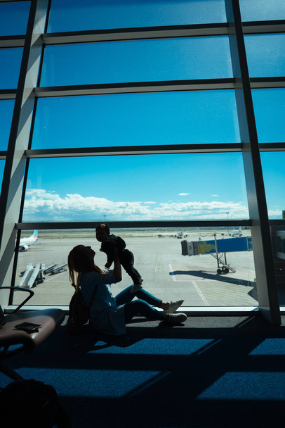 Küçük bir çocuk ve annesi bir havaalanında oturuyor - Fotoğraf, Görsel
