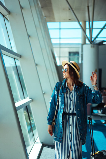 Женщина отправляется в путешествие с чемоданом в аэропорту - Фото, изображение