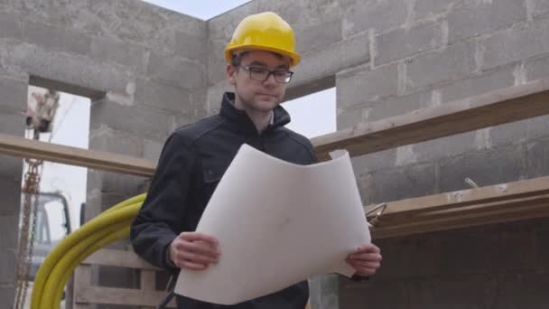 Keresi a nagy terv fiatal építőmunkás. - Felvétel, videó
