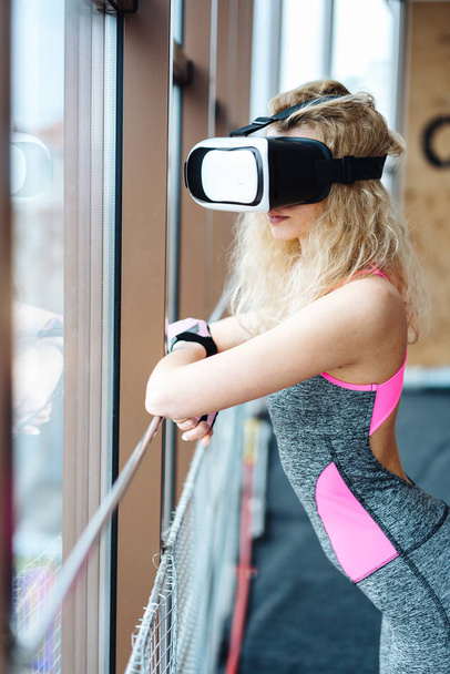 Beautiful girl in the gym with VR headset - 写真・画像