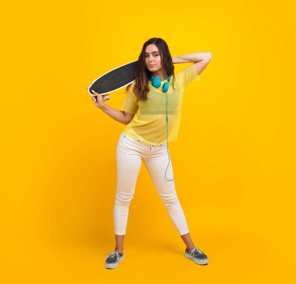 Brunette teen with skateboard standing - Фото, зображення