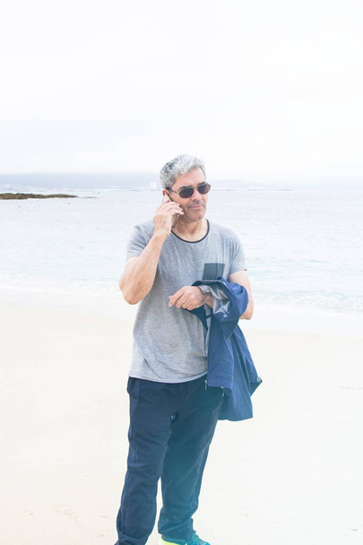Senior man talking on the phone at the beach - Foto, Imagem