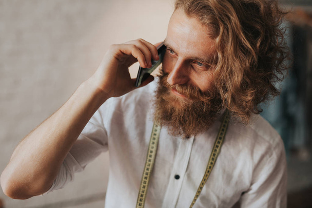 Bearded tailor talking on phone - Fotó, kép