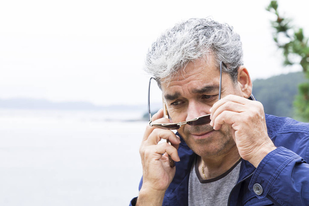 Senior man talking on the phone at the beach - Valokuva, kuva