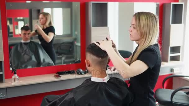 Ο στυλίστας εκσυγχρονίζεται το χτένισμα ενός άνδρα, η γυναίκα prunks τα μαλλιά της - Πλάνα, βίντεο