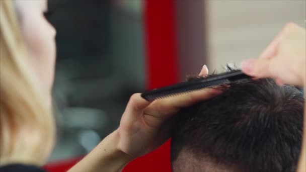 Cabeleireiro mulher fazendo corte de cabelo para o jovem. Ela usa tesouras e pente
 - Filmagem, Vídeo