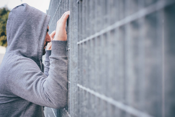  Homem solitário encostado a uma cerca
 - Foto, Imagem
