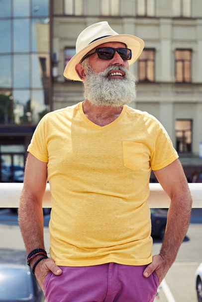 Stylish mature bearded man in bright yellow t-shirt and hat  - Photo, Image