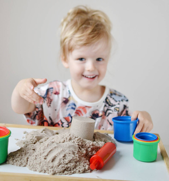 Pieni tyttö leikkii kineettinen hiekka kotona Varhaiskasvatus
  - Valokuva, kuva