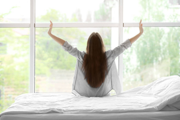donna che si estende dopo il sonno contro la finestra
 - Foto, immagini