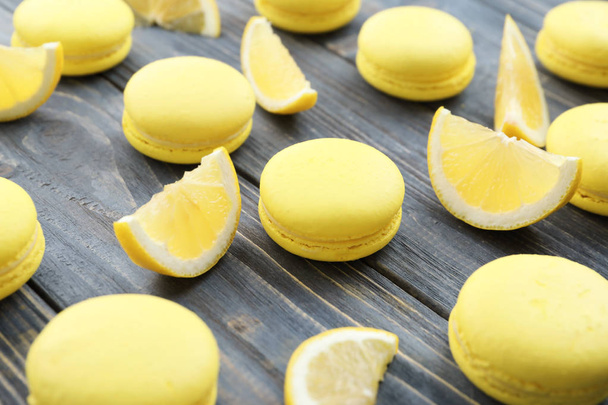 Tasty fresh macarons and lemon slices on wooden table, closeup - Foto, Imagen