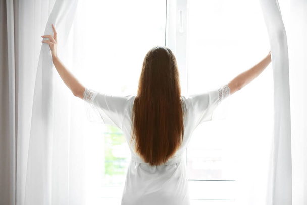  жінка дивиться у вікно вдома
 - Фото, зображення