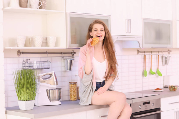 young woman having breakfast in kitchen - 写真・画像