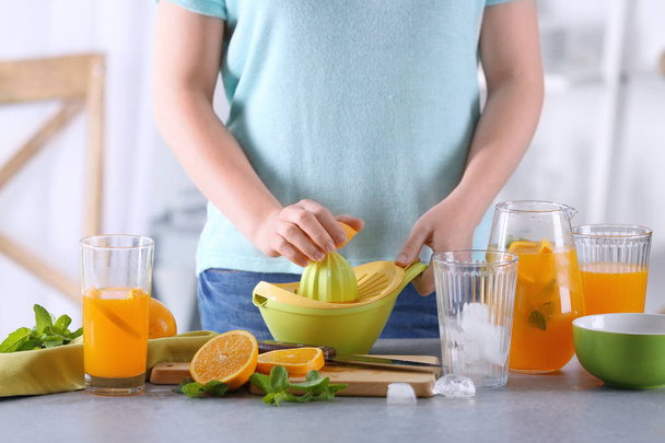 Woman preparing orange lemonade in kitchen - 写真・画像